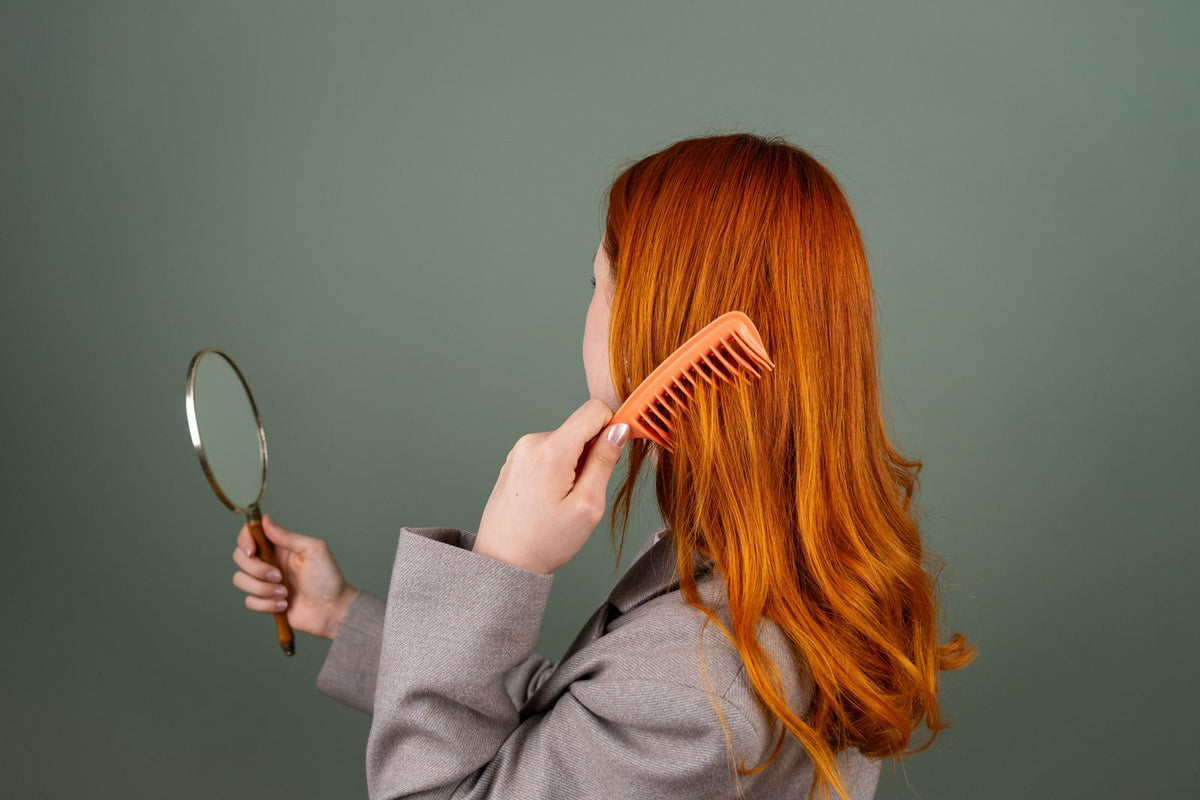 Frau kämmt ihre Haare vor einem Handspiegel