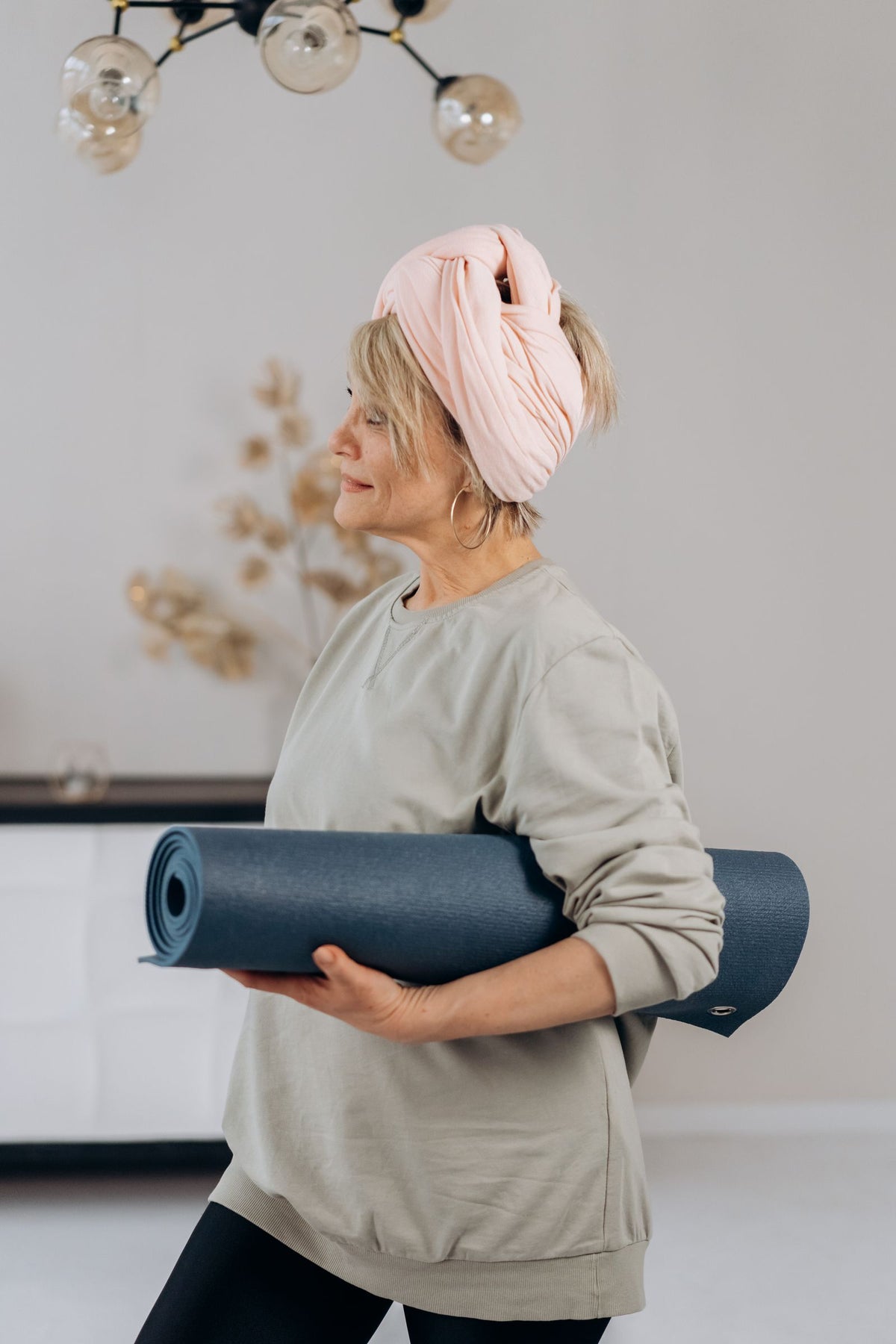 Lächelnde ältere Frau mit einer Yogamatte