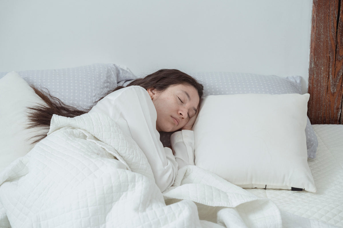 Frau schläft entspannt auf der Seite in einem hellen Bett
