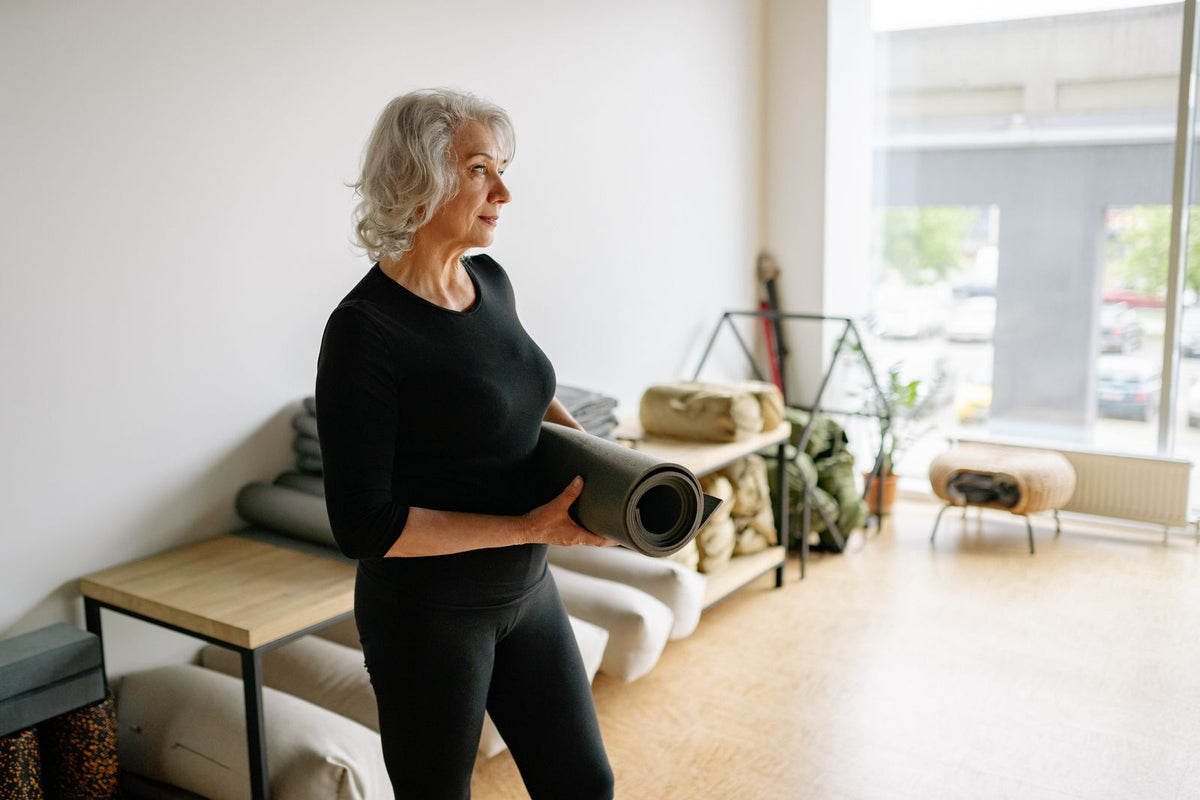 Aktive ältere Frau mit Yogamatte