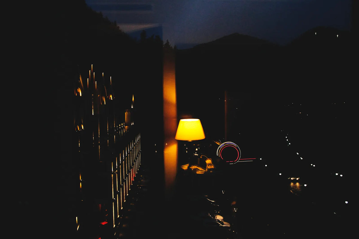 Eine leuchtende Nachttischlampe im dunklen Schlafzimmer. Foto: George Shervashidze / Pexels.
