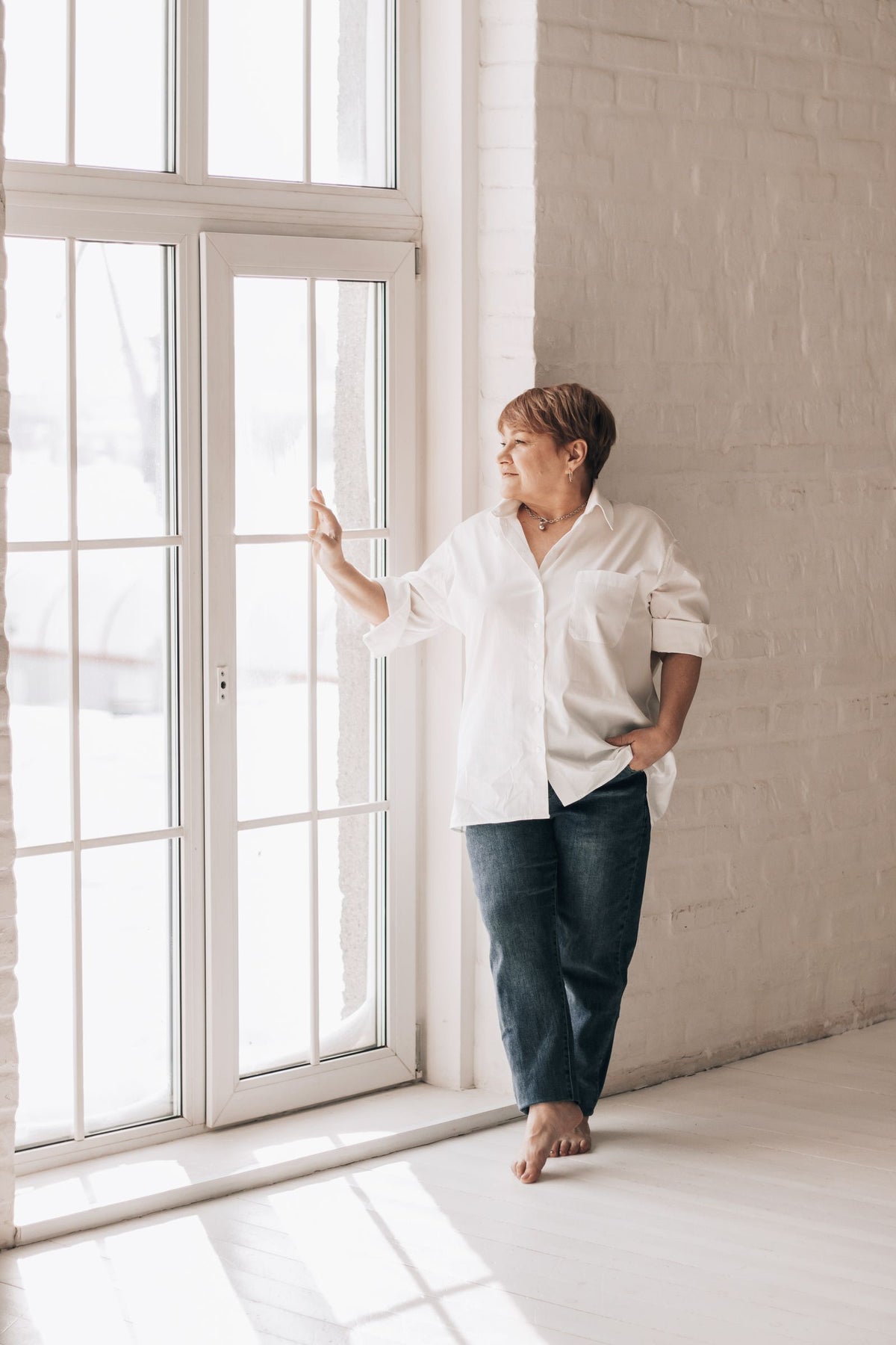 Frau in der Lebensmitte am Fenster
