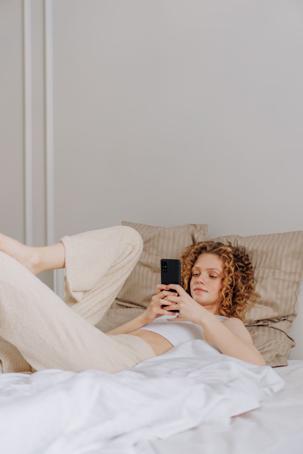 Frau liegt im Bett und benutzt ihr Smartphone