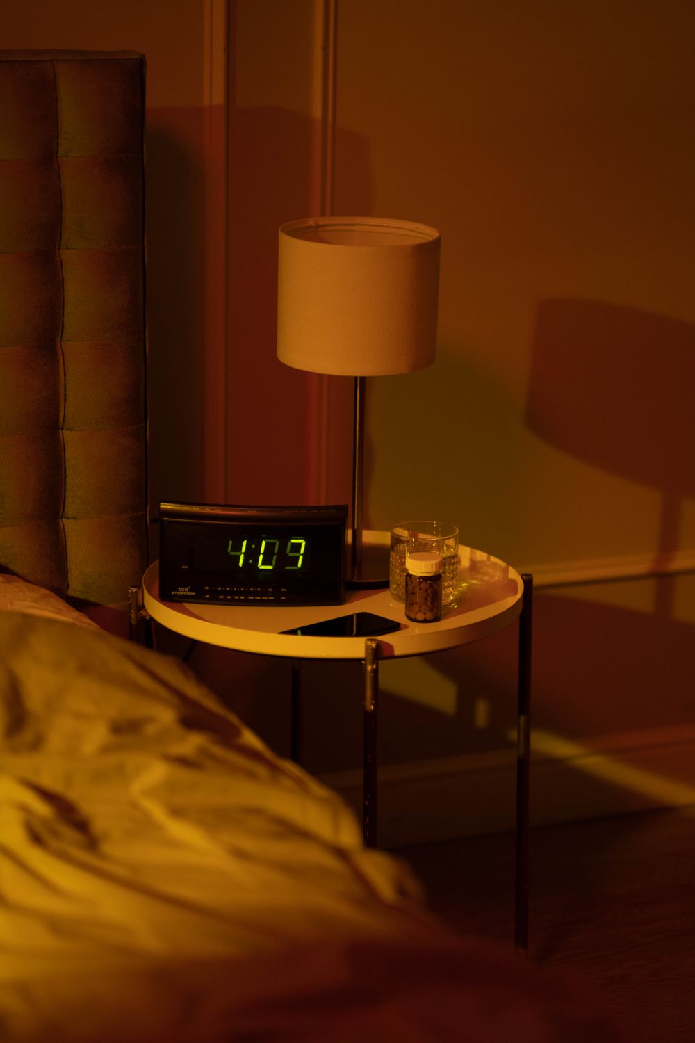 Nachttisch mit Lampe und digitalem Wecker bei Nacht