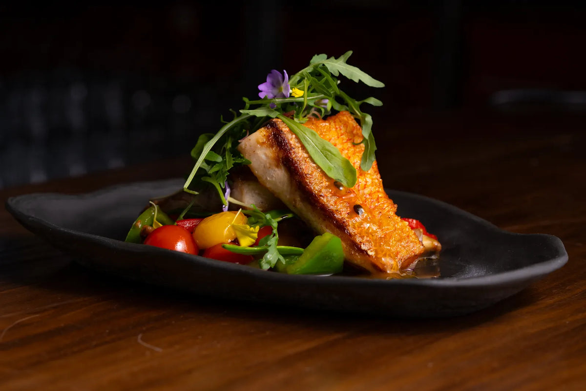 Lachs mit Tomaten und frischem Gemüse auf einem Teller. Foto: Nano Erdozain / Pexels.