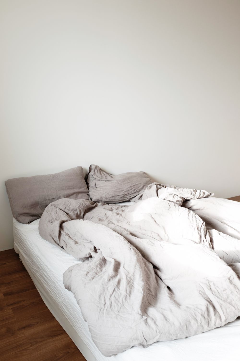 Helle Bettwäsche und Kissen in einem ruhigen Schlafzimmer