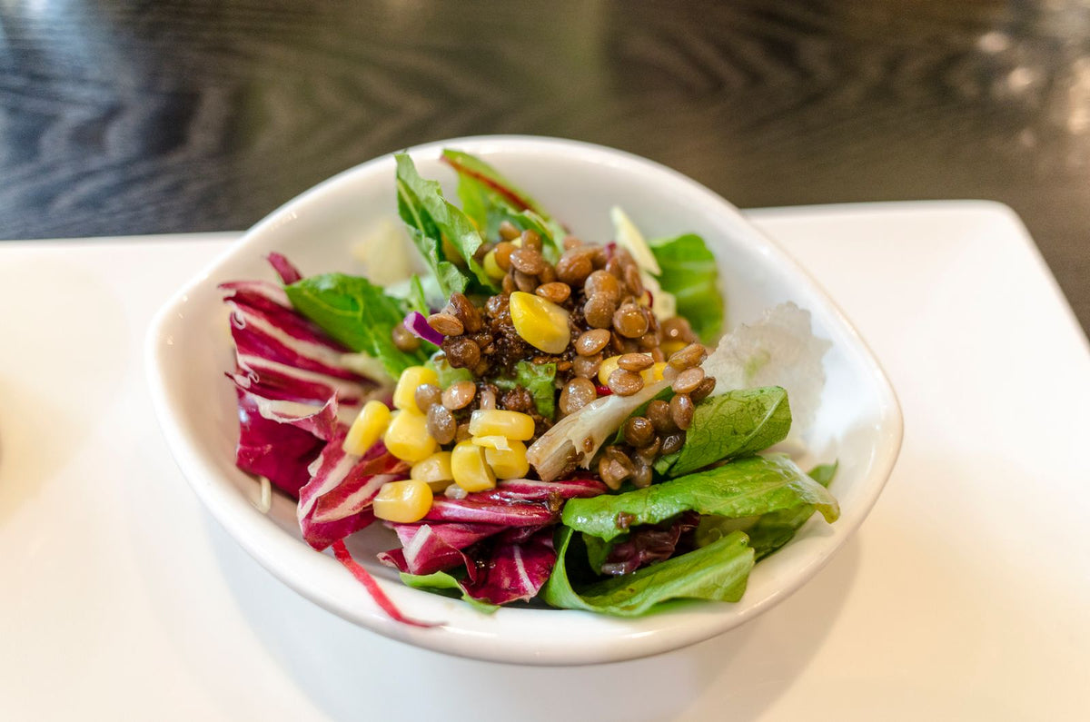 Gemüsesalat mit Linsen und Mais in einer weißen Schale