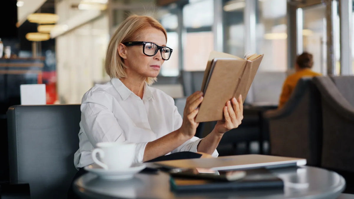 Eine Frau liest konzentriert ein Buch im Café. Foto: Vitaly Gariev / Pexels.