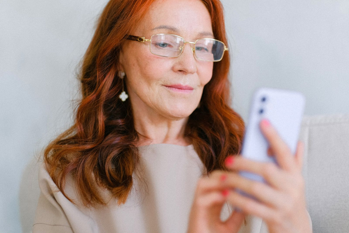 Frau in der Lebensmitte mit Brille und Smartphone