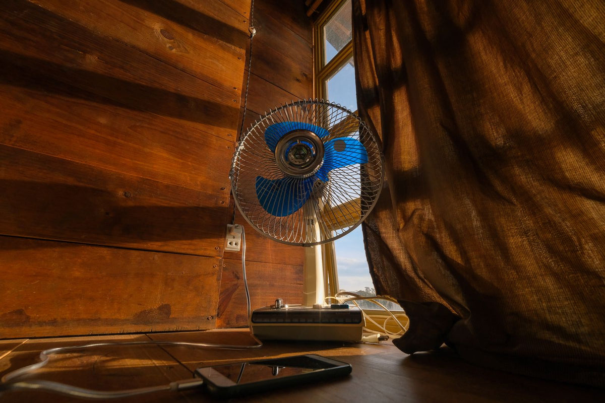 Ventilator am sonnenbeschienenen Fenster – Illustration zum Abkühlen bei Hitzewallungen