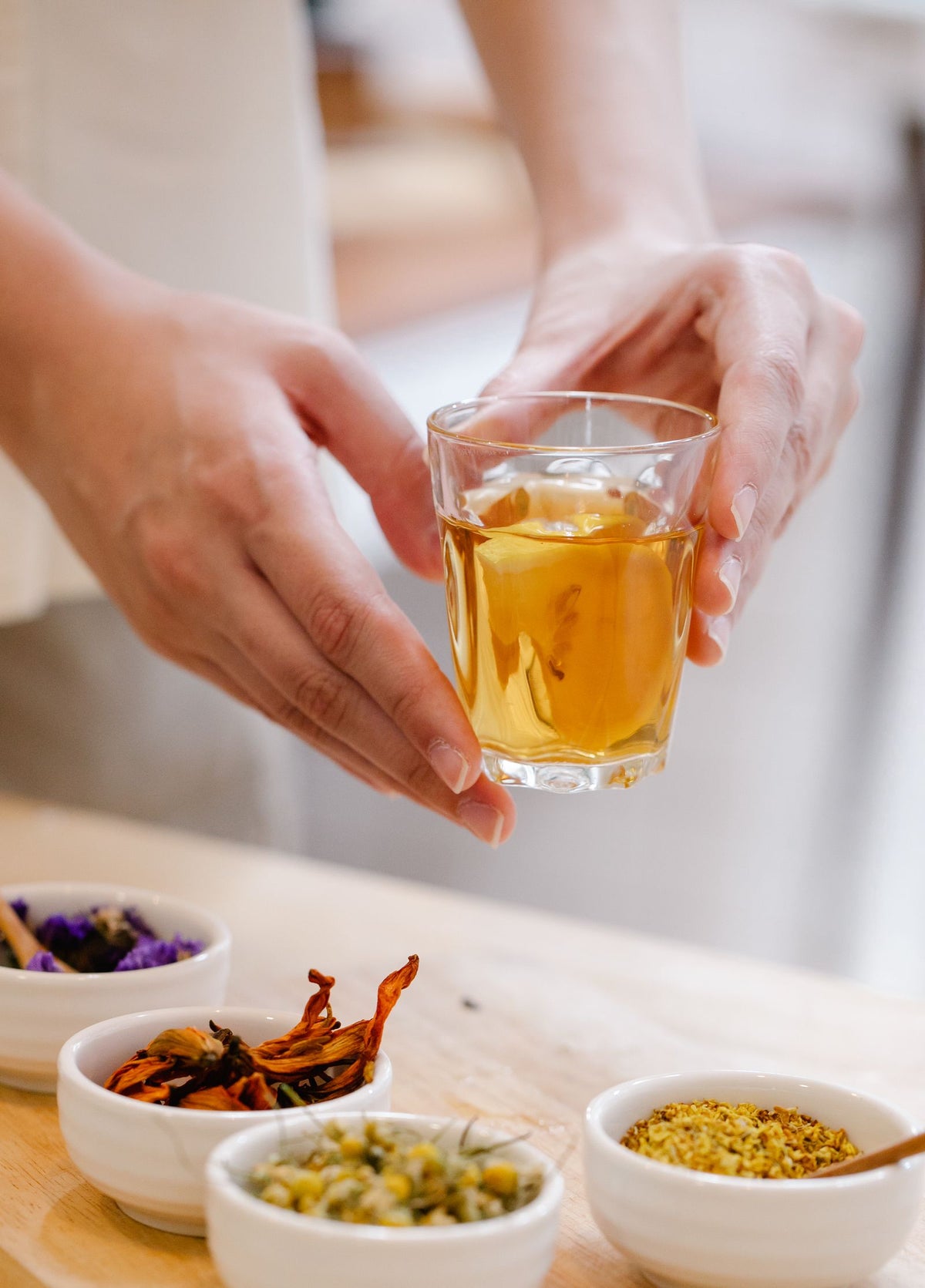Hände halten ein Glas Kräutertee in einer ruhigen Alltagsszene