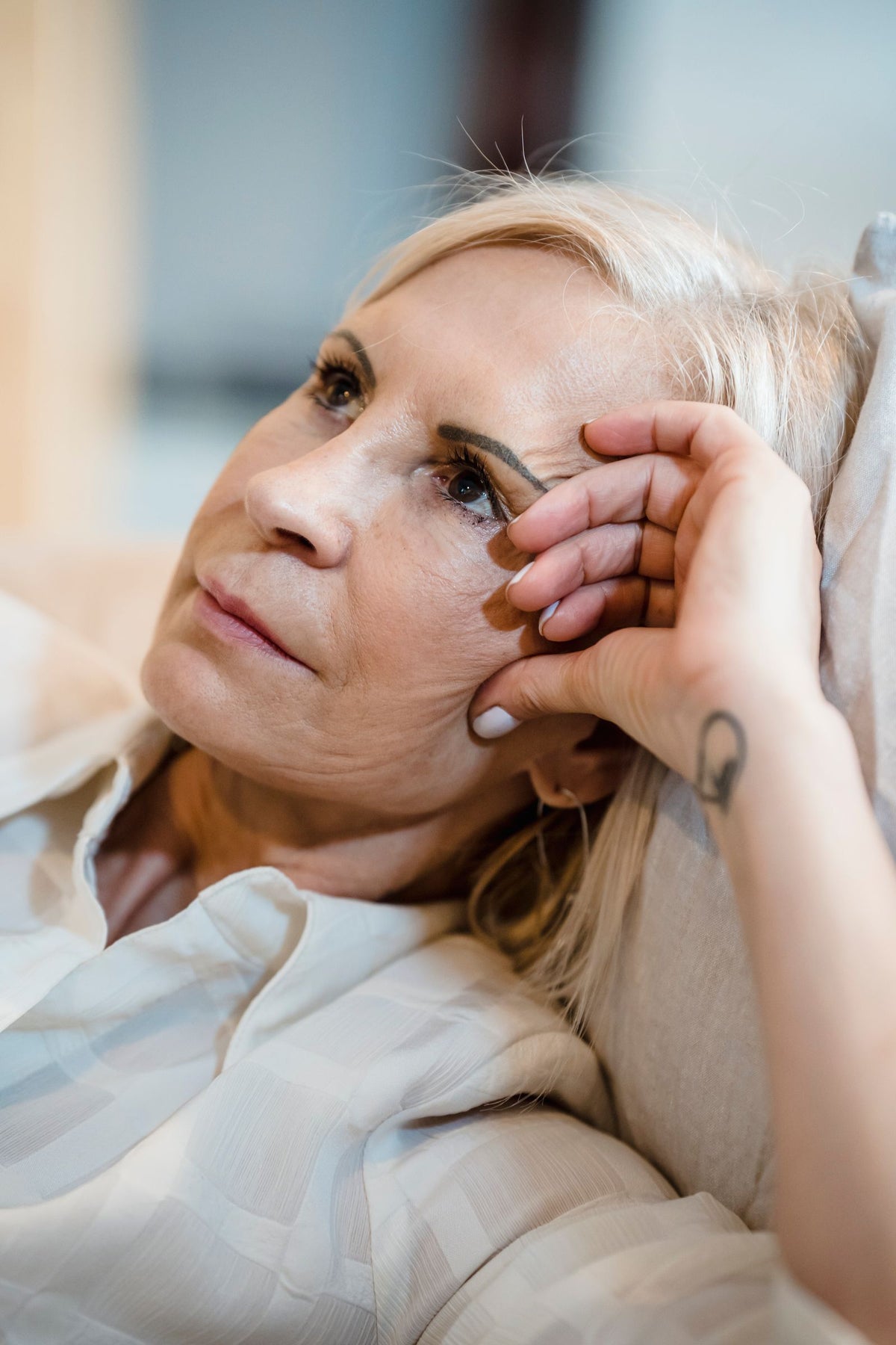 Frau ruht in einem hellen Innenraum auf einem Sofa