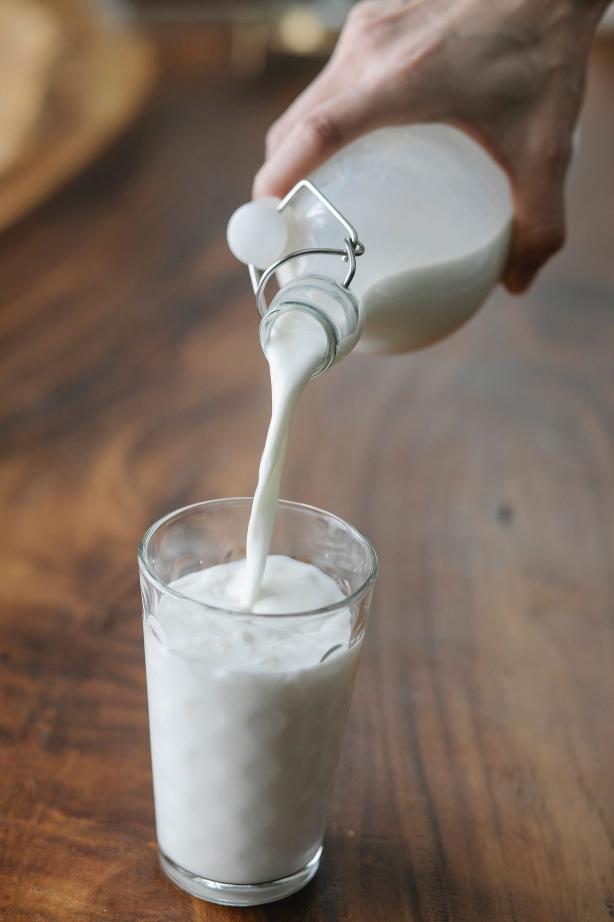 Milch wird aus einer Flasche in ein Glas gegossen
