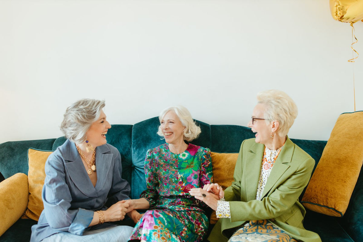 Drei Frauen lachen gemeinsam auf einem Sofa