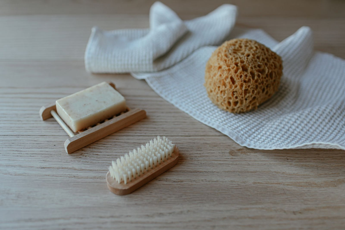 Seife, Bürste und Naturschwamm auf einem hellen Handtuch