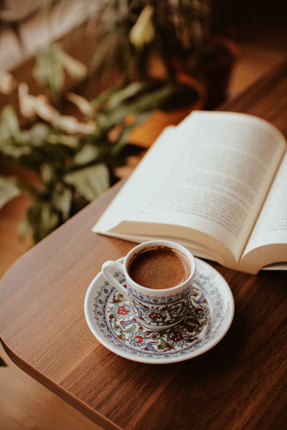 Kaffeetasse und aufgeschlagenes Buch auf einem Holztisch