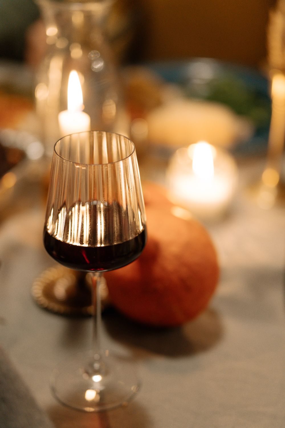 Glas Rotwein auf einem gedeckten Tisch bei Kerzenlicht