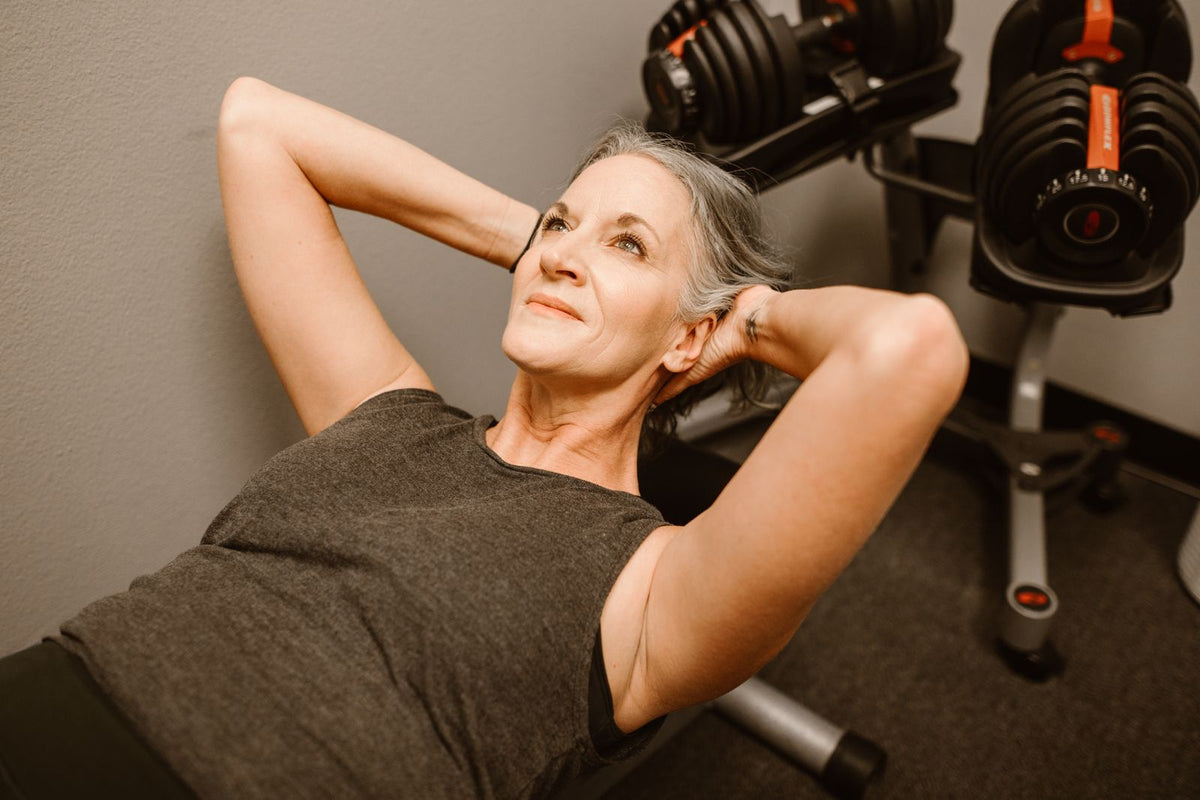 Frau trainiert auf einer Bank im Fitnessstudio